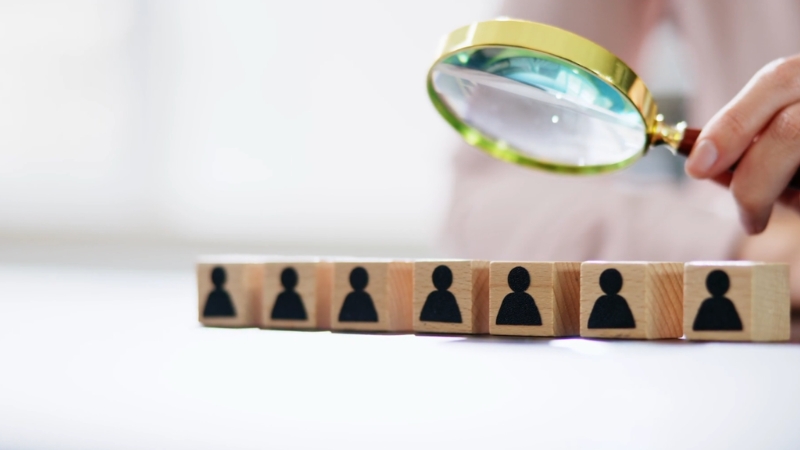 Ruka drži lupu iznad drvenih kockica sa siluetama ljudi, simbolično prikazuje razliku između preduzetnika i DOO