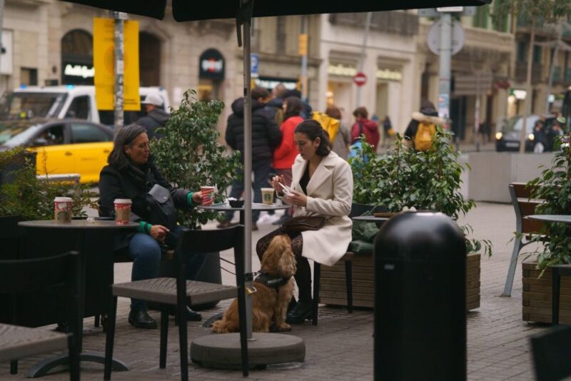 Ljudi sede u bašti kafića i razgovaraju u urbanoj gradskoj atmosferi