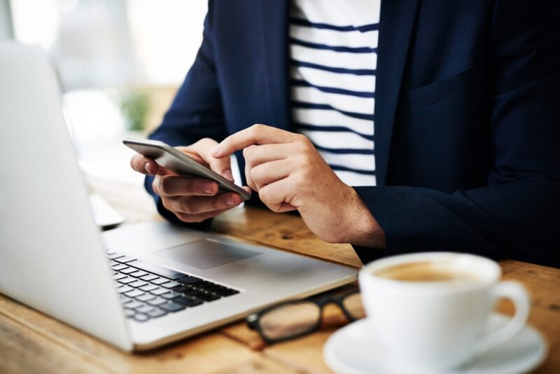 Osoba koristi telefon i laptop dok proverava online komentare i recenzije