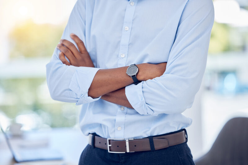 Muškarac u svetloplavoj košulji i tamnim elegantnim pantalonama sa kožnim kaišem i ručnim satom kao primer business casual oblačenja