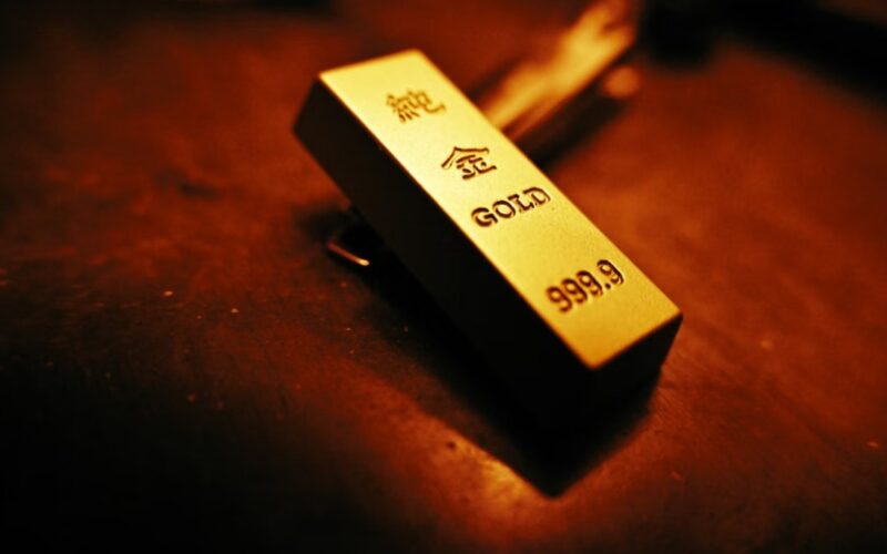 Zlatna poluga finoće 999,9 sa oznakom GOLD i kineskim karakterima, postavljena na tamnu površinu pod toplim osvetljenjem